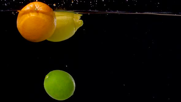 Vibrant citrus fruits floating through water in slow motion. alt