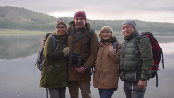 Group of Senior Tourists Posing for Camera on Lakeshore alt