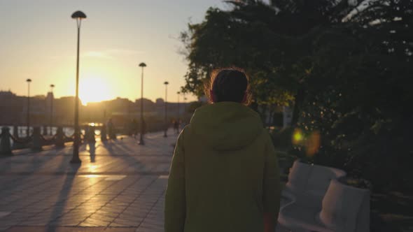 A Girl in a Yellow Coat Walks at Sunset
