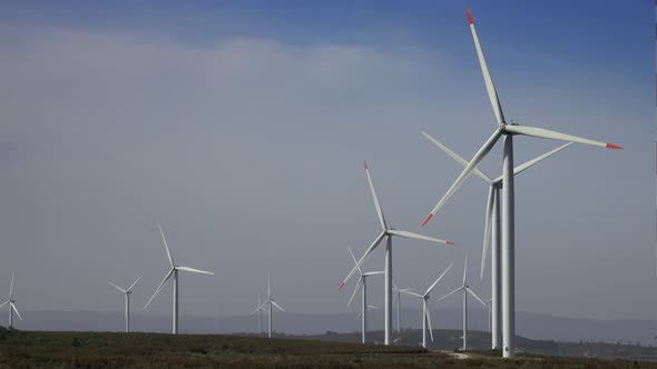 Windmills or Wind Turbine on Wind Farm in Rotation alt