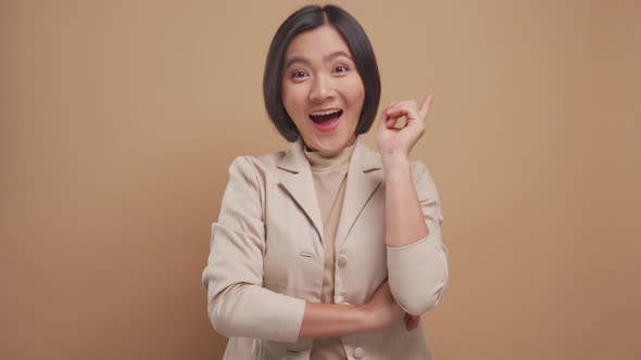 Happy business asian woman have a good idea crossed arms standing isolated over beige background.