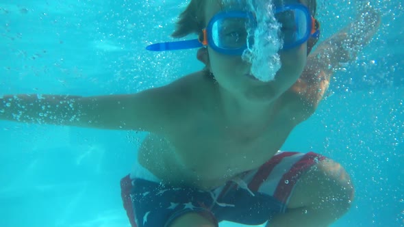Underwater shot of a boy playing in a pool at a hotel resort. alt