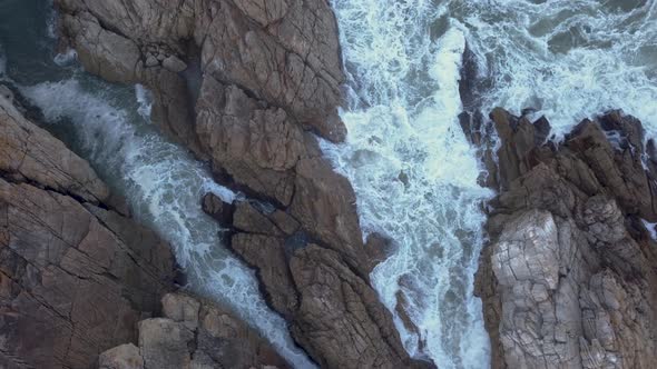 Aerial view over waves breaking onto rocks in the ocean