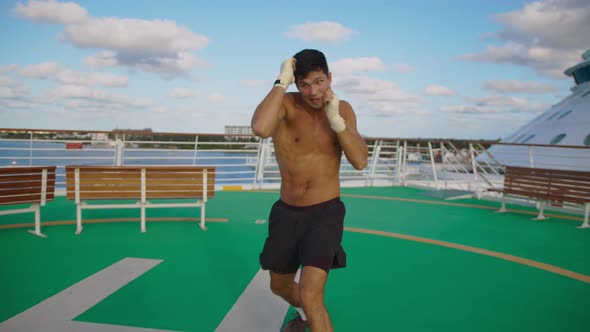 Attractive Man Kicks Fast Punches Exercising Shadow Boxing on Helipad Onboard Cruise Ship
