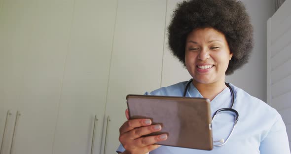 Video of happy plus size african american female doctor using tablet alt