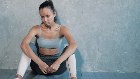 Pretty woman wearing sportswear.Beautiful girl sitting after training in studio alt