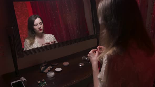 Young Caucasian Woman Puts a Choker on Her Neck While Sitting in the Bedroom By the Mirror in the alt