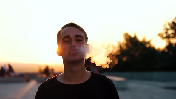 Guy Smokes an Electronic Cigarette at Sunset