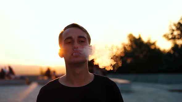 Guy Smokes an Electronic Cigarette at Sunset alt
