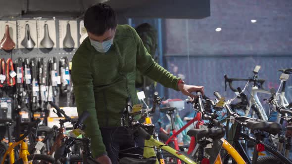 Shopper in Sterile Mask Selecting Mountain Bicycles in Sports Shop alt