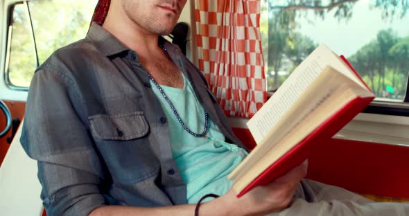 Man reading novel while having coffee in camper van 4k alt