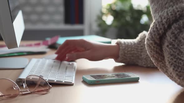 Young Woman Scrolling and Texting Using her Smartphone and Computer alt