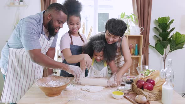 Happy African American family preparing flour to make bread in kitchen at home.