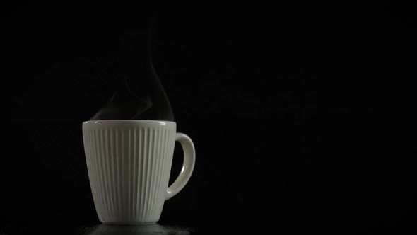 Cup of hot drink with steam on a dark background. alt