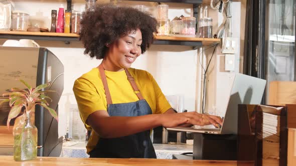 African American female barista cheerful works with smile at cafe counter bar.
