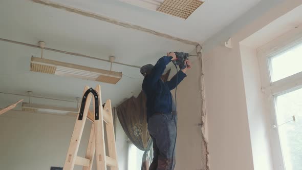 The Master Builder Drills a Hole in the Wall During the Repair Work in the Room alt