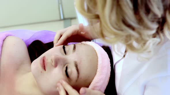 Relaxed woman lying on spa bed for facial and head massage spa treatment by massage therapist alt