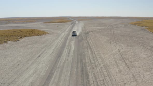 Front View Of 4x4 Car Driving On A Dusty Makgadikgadi Salt Pan On A Sunny Summer Day In Botswana. - alt