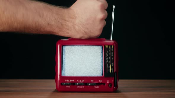 Knocking on Small Old Television with Grey Interference Screen on Black Background alt