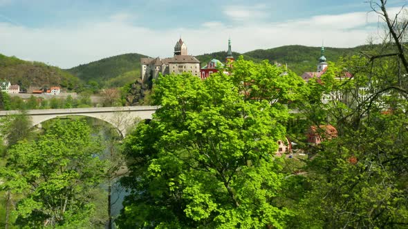 Flight Over Loket Castle Surrounded By River Ohri and Small Houses on a River Shore Near Kariovy alt