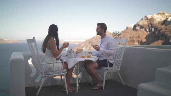 Young Couple Having Breakfast Outside on Terrace on Santorini Island