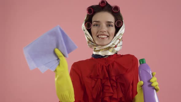 A Woman with Curlers on Her Hair Cleans an Invisible Surface with a Cloth