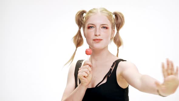 Young Beautiful Girl Dancing Smiling Holding Chupa Chups Over White Background alt