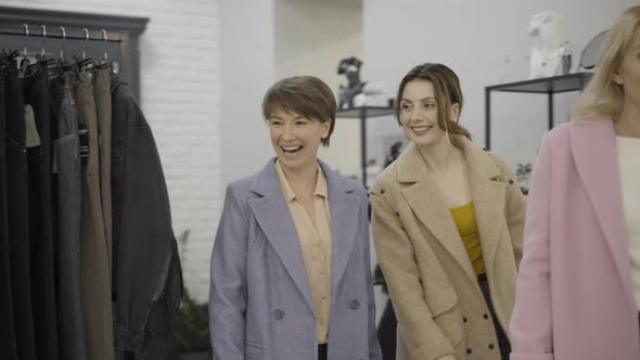 Three Confident Beautiful Women Entering Clothing Store, Talking and Smiling. Portrait of Rich alt