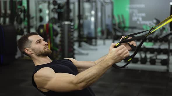 Side View of Strong Sportsman Doing Exercises with TRX Straps at Gym alt