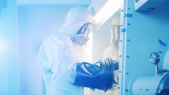 Specialist in a Hazmat Suit Is Working with a Vacuum Cabinet alt