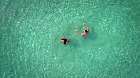 Aerial view of man and woman preparing to snorkel in turquoise sea. alt
