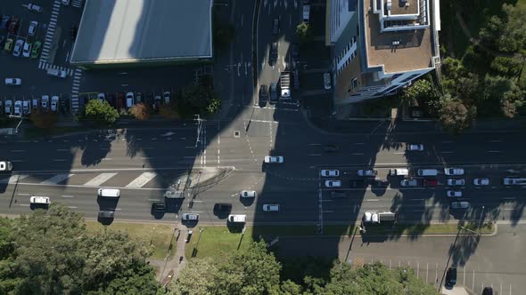 Cars passing the busy highway and T intersection. Aerial horizontal top down view on a sunny day. alt