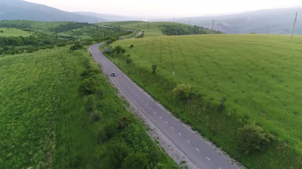 panorama of the mountain landscape. a black car is driving along the road. alt