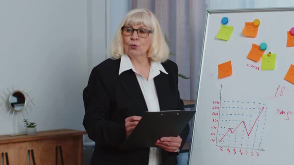 Senior Business Woman Coach Leader Conference Speaker Explain Project Strategy on Office Whiteboard alt