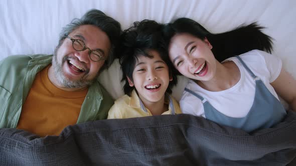 happiness asian lovely family lay down together on bed ,smiling and laugh