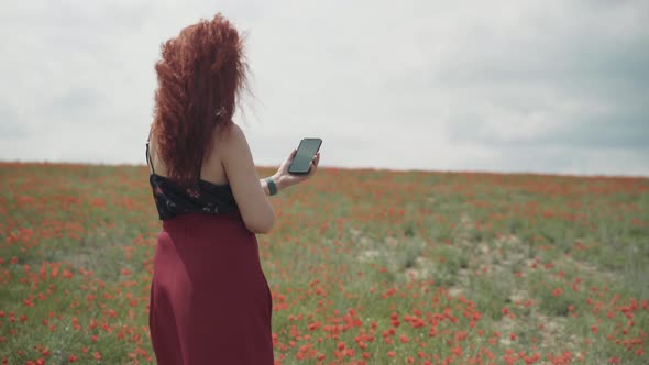 Girl with Mobile Phone in Poppy Field