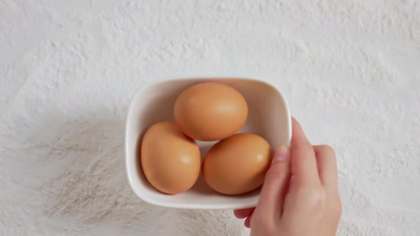 Hand hold the cups for eggs and flour on the table with for making various desserts alt