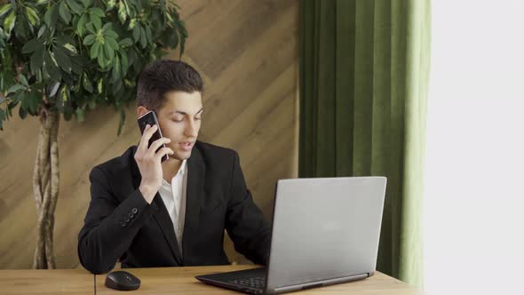 Arabic Businessman Works in a Modern Office with a Pc and Talks on the Phone Working with a Laptop alt