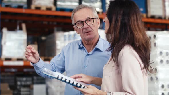 Mature woman and man analyzing documents in the warehouse. Shot with RED helium camera in 8K. alt