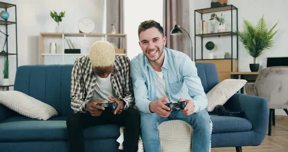 Smiling Gay Couple which Spending Joint Leisure at Gaming at Home alt
