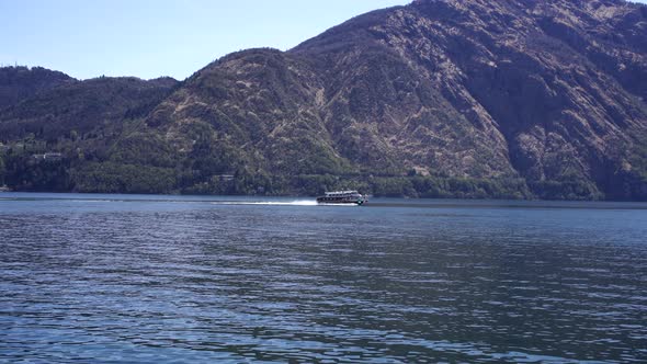 Tourist Boat Floats on Lake Como Against the Backdrop of Mountains