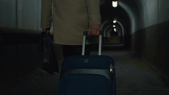 Man with rolling bag walking in the tunnel