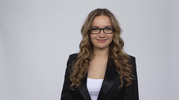 Woman Pointing Side Hand for Something Then Nods Approvingly with Copy Space Over Grey Background. alt