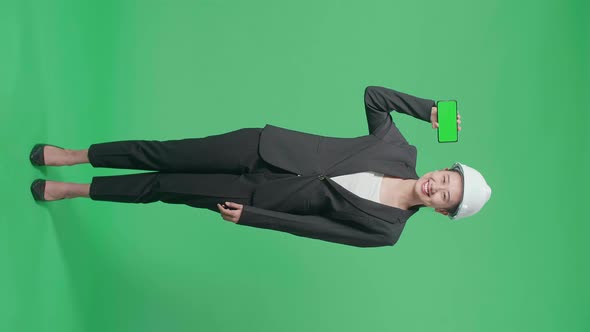 Full Body Of Smiling Asian Female Engineer Showing Green Screen Smartphone On Green Screen alt