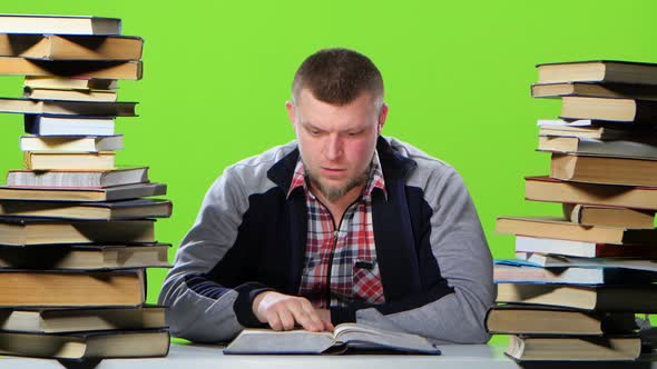 Man Sitting at a Table and Reads the Information Is Surprised. Green Screen alt