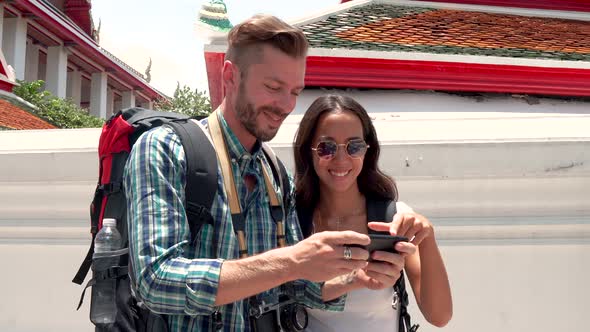 Lovely young tourist couple taking selfie with smartphone at Thai temple