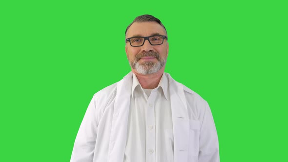 Mature Doctor Listening To Someone Behind the Camera and Smiling on a Green Screen Chroma Key alt