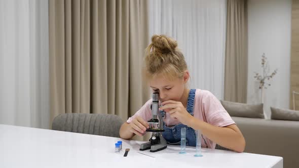 Preteen Girl Using Microscope at Home Doing Research