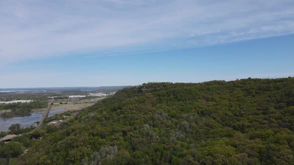 View over tree covered mountain with wispy clouds and blue sky. Wetlands and train tracks.