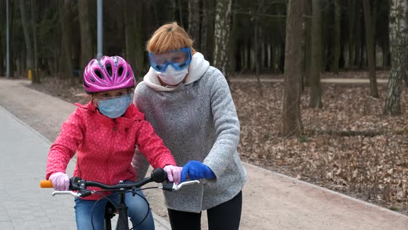 Mom teaches her daughter to ride a bike in the city Park. 